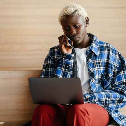 black woman talking on smartphone while surfing internet on laptop