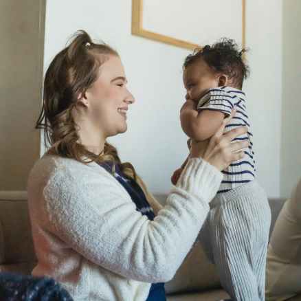 optimistic mother with black baby in hands