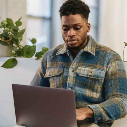 young ethnic man working remotely on netbook at home