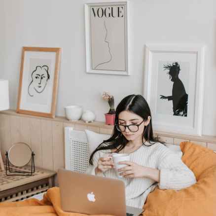 woman having coffee and using laptop in bed
