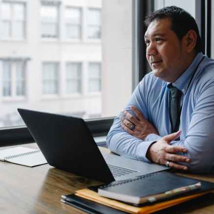 positive ethnic boss using laptop in light office