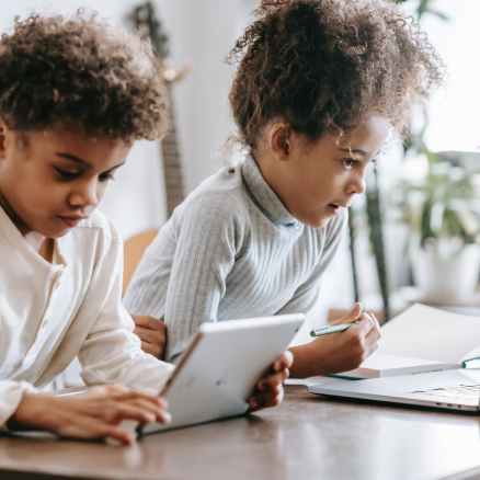 concentrated black children using laptop and tablet at home