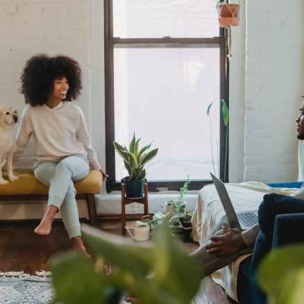 positive young black couple chatting while spending weekend together at home with cute dog