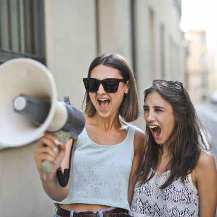 cheerful young women screaming into loudspeaker
