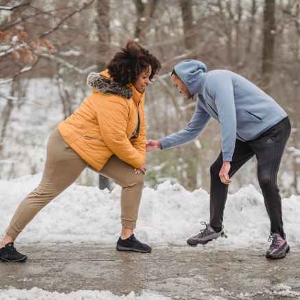coach correcting black woman while doing lunges in park
