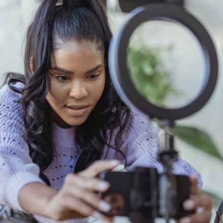 black woman recording video with smartphone near ring lamp